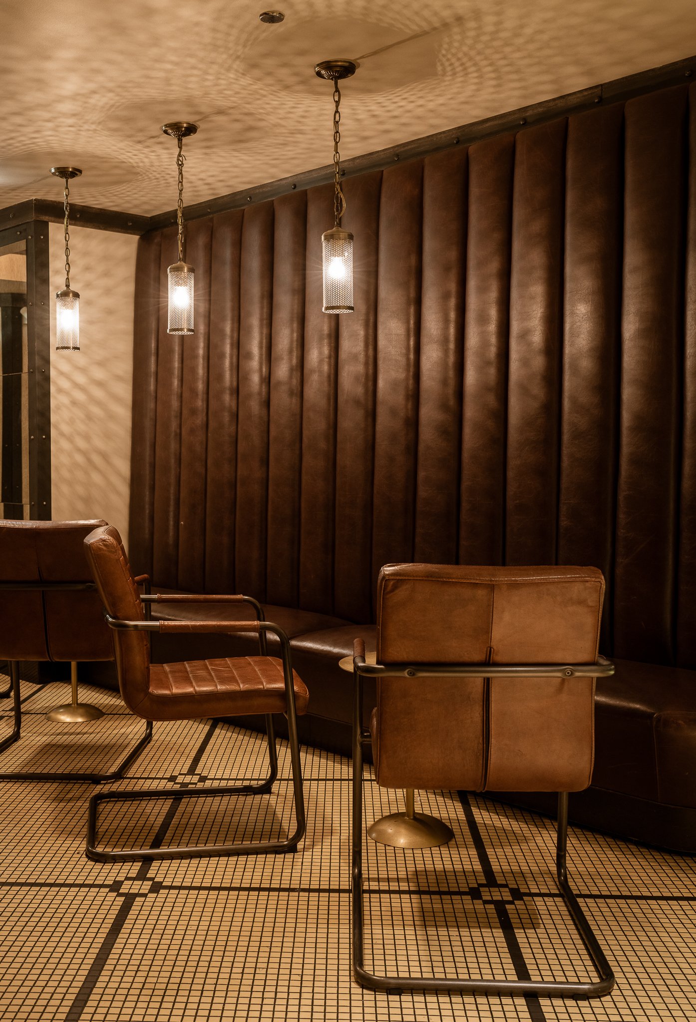 Close-up of cozy side seating area, featuring leather booth, chairs, and small cocktail tables