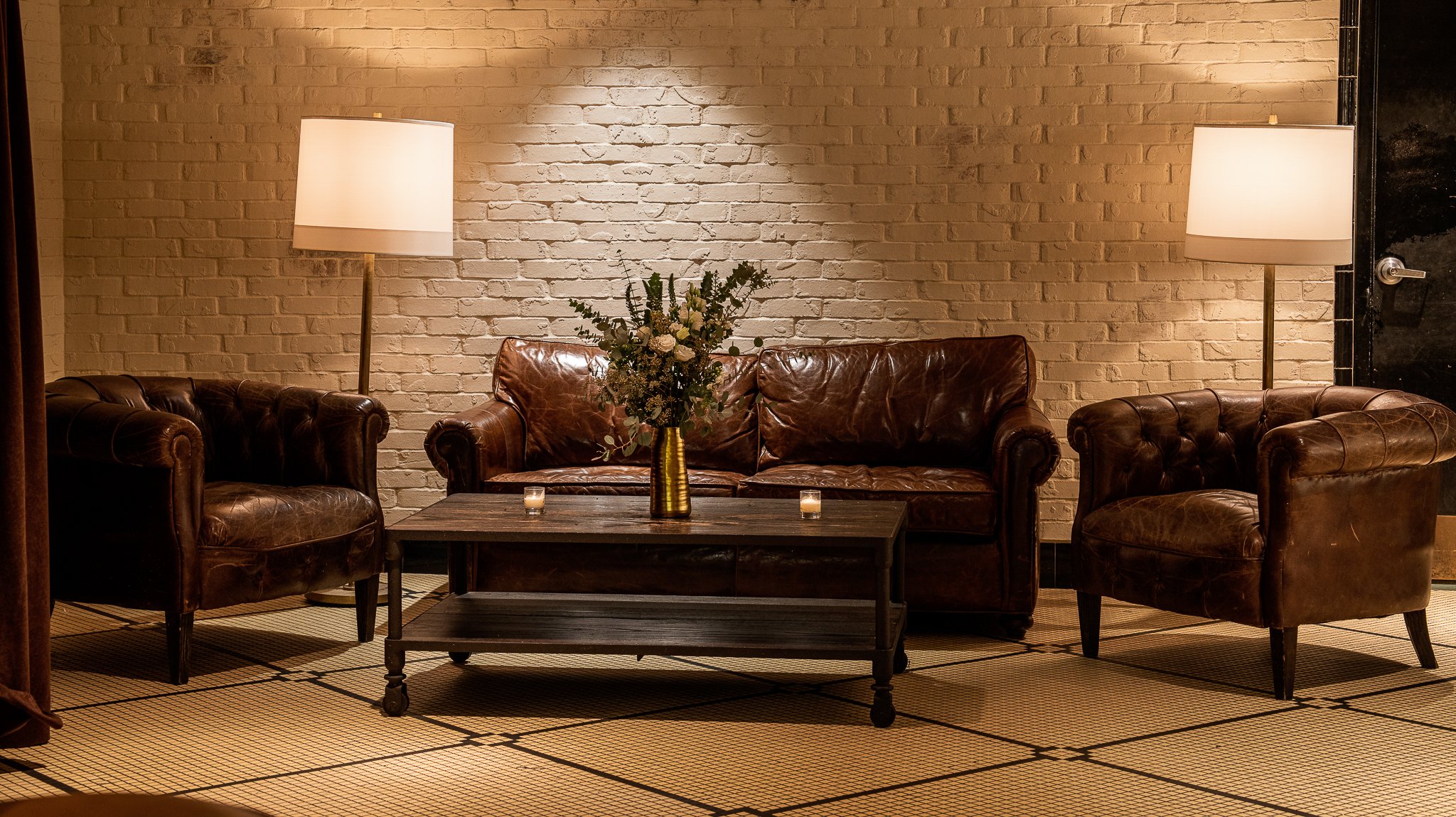 Cozy seating area near Theodore Asher bar: leather couches, warm lighting