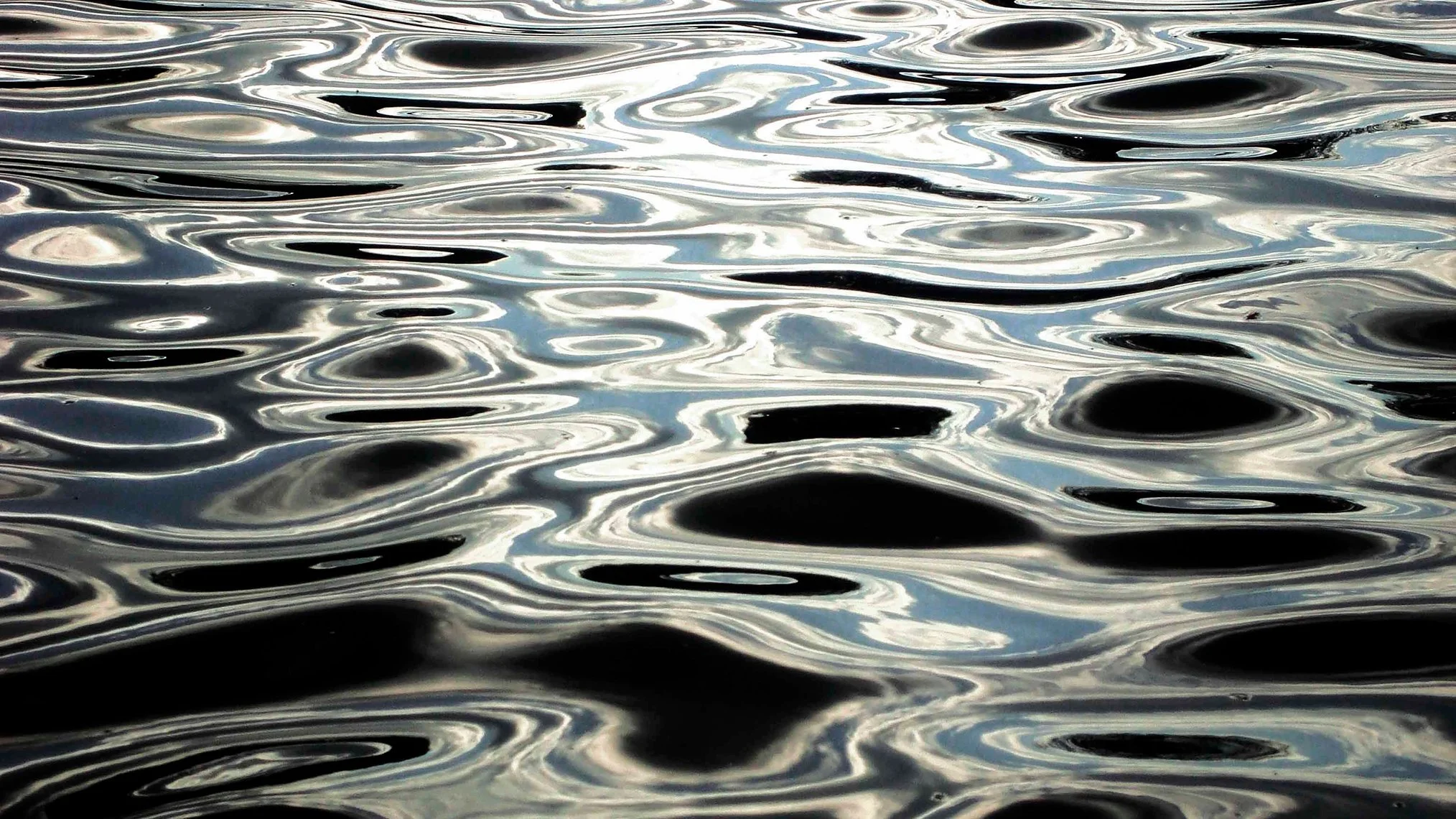 A photograph of ripples on water reflecting the light.