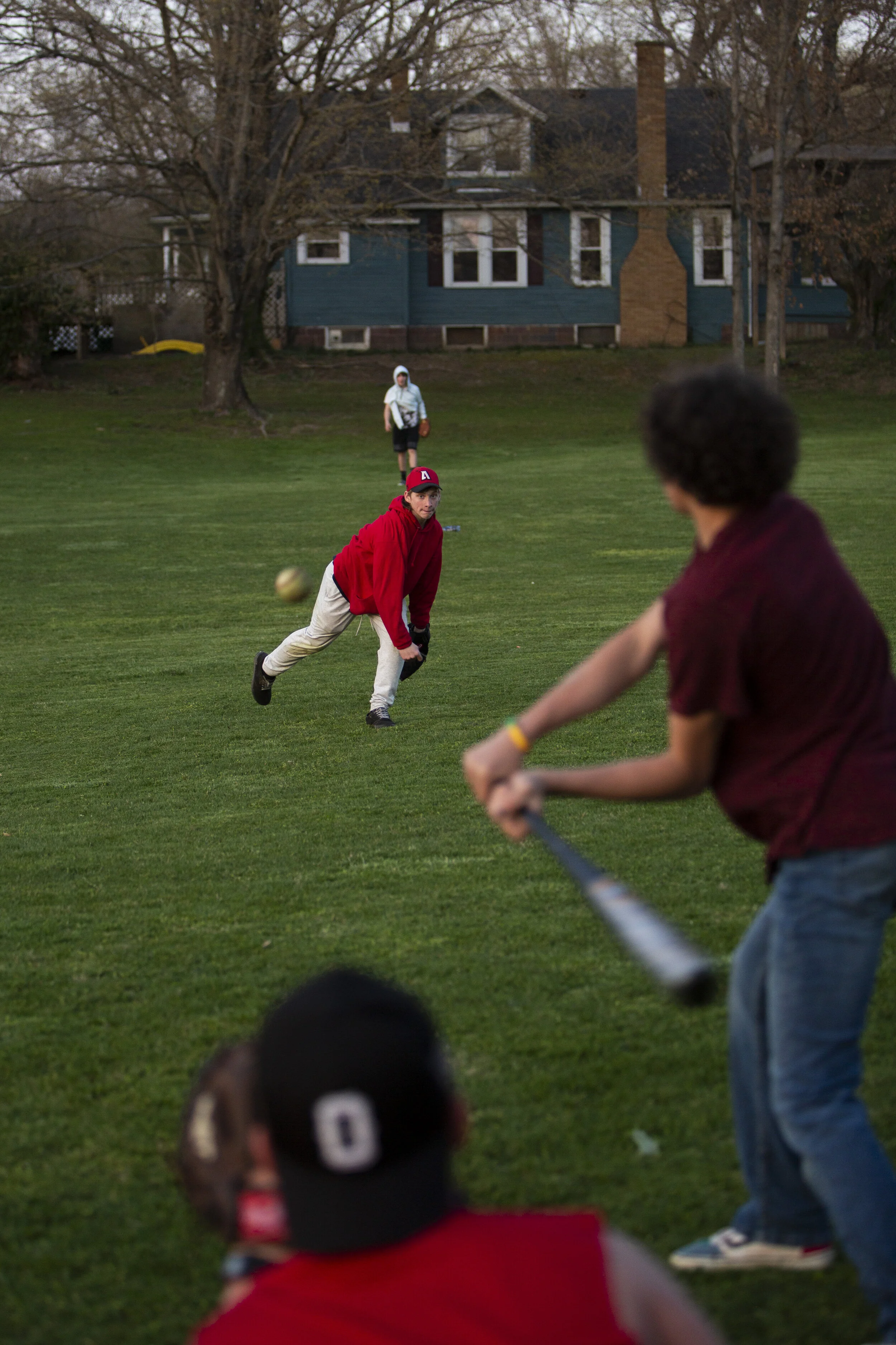  Andrew Wheeler, 15, throws a pitch while Addam Eblin, 15, sits ready to catch it as DJ Gonzalez begins to swing at it on Saturday, April 4, 2021. Kids and teenagers often bike throughout the town and play in the field and park at the center of town 