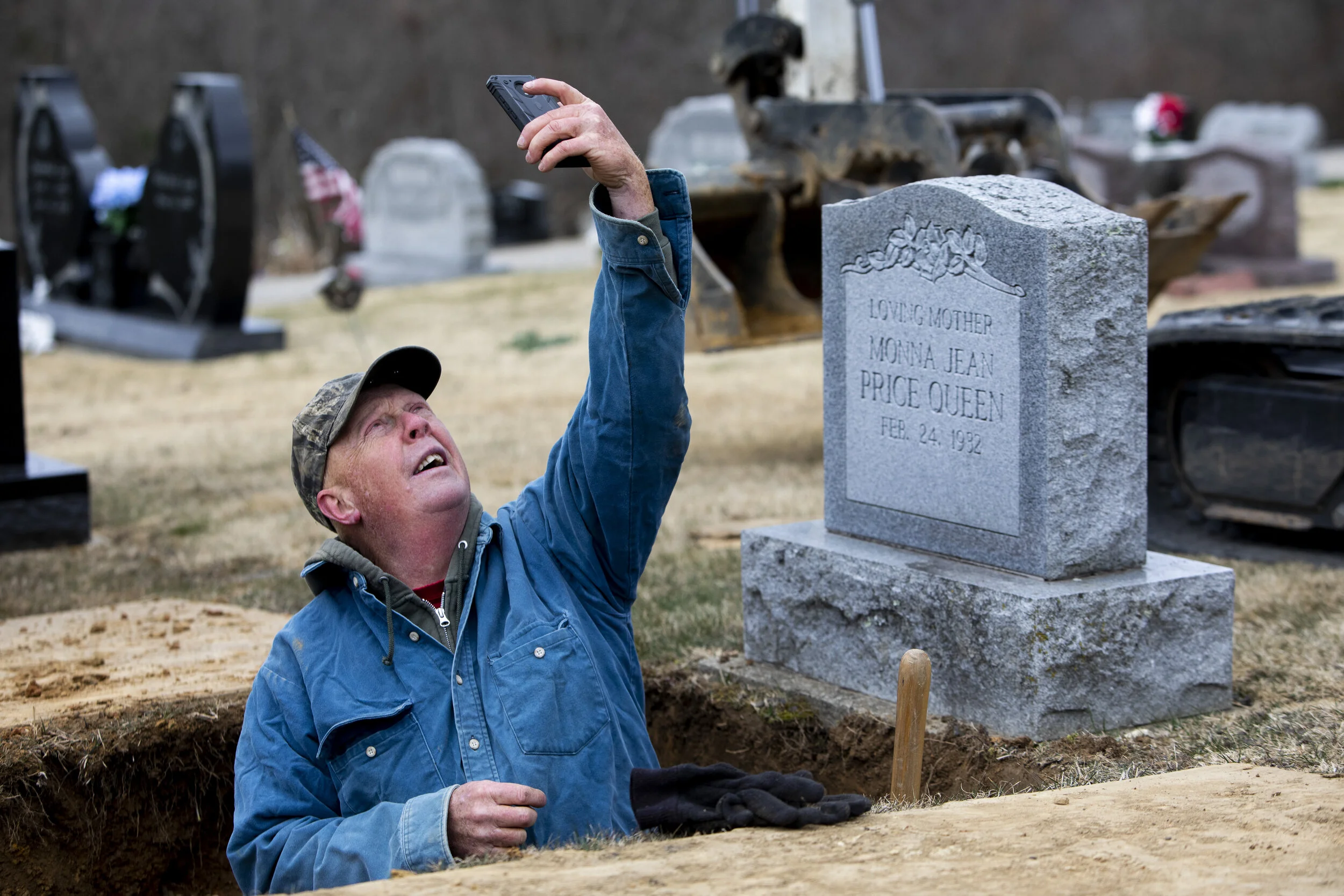  Bruce Chaney tries to get reception on his phone after he finishes digging a grave to check the weather and see if he will need to cover the hole from rain on Monday, March 15, 2021. Chaney has worked for the Waterloo Township since 2004 and has loo