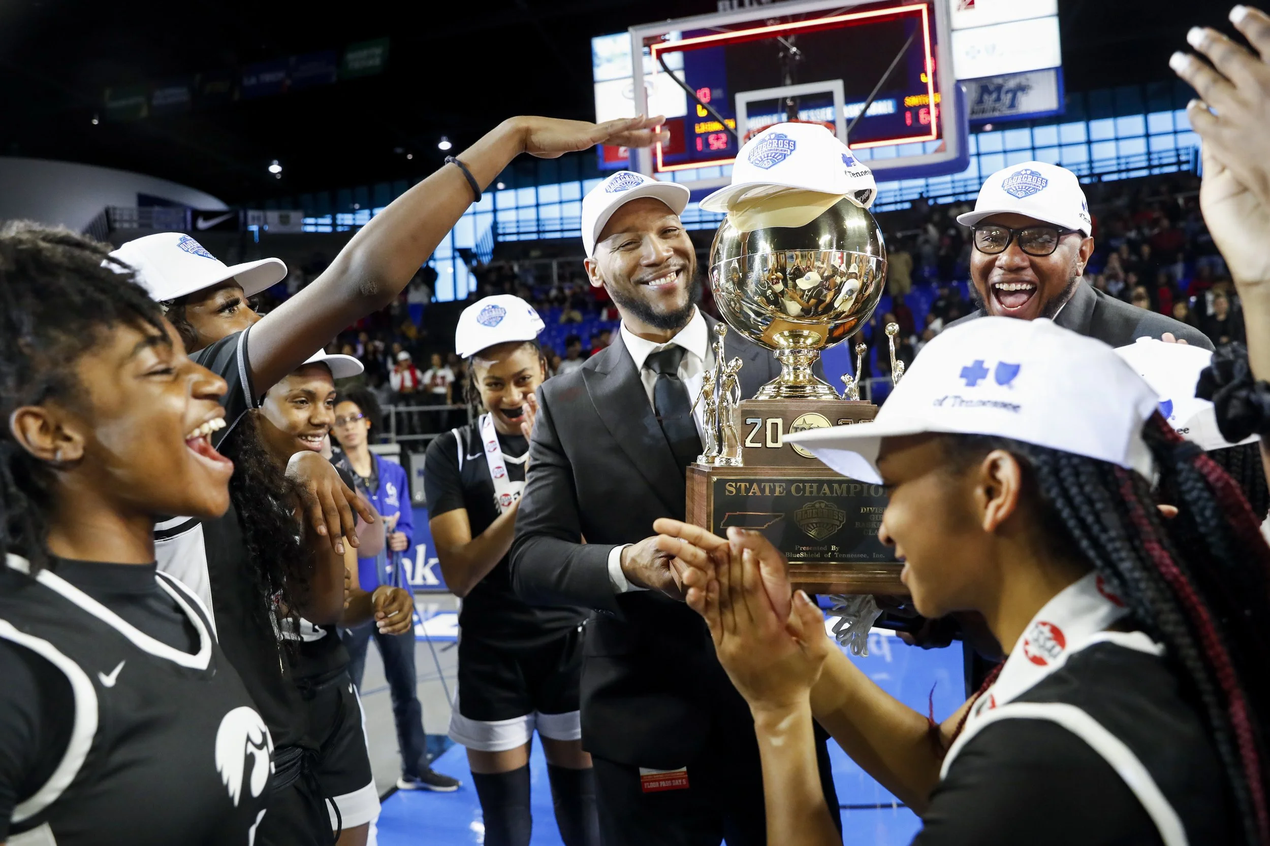  South Side's Head Coach Brent McNeal holds up the state championship trophy as South Side players cheer and fan the trophy after placing a hat on it after they won against Livingston Academy 62-52 in the TSSAA BlueCross Girls’ Basketball Championshi