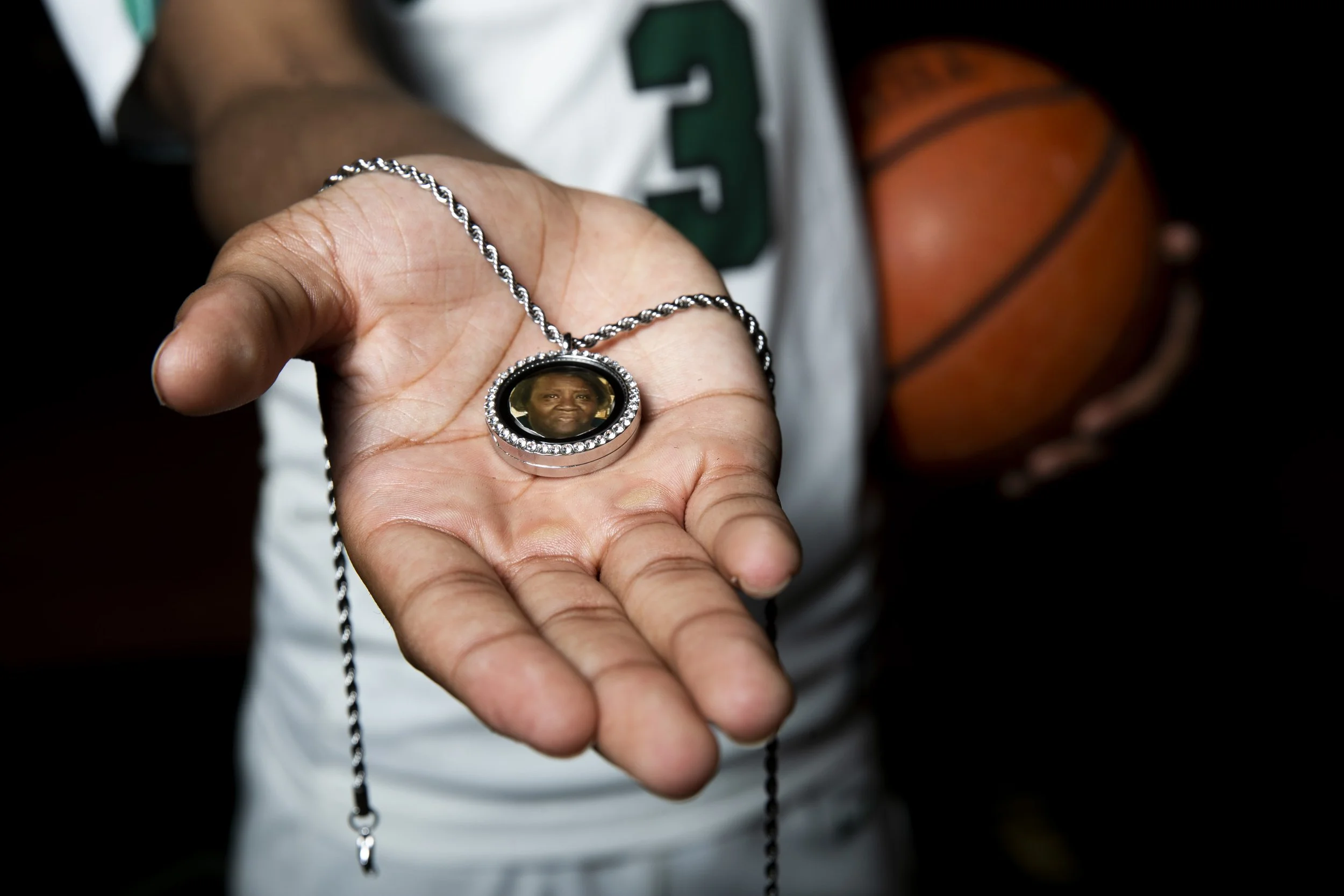  Cordova’s KJ Tenner poses for a portrait holding a necklace with a picture inside of his late grandmother Ophelia Jones in the gym at Cordova High School in Cordova, Tenn., on Wednesday, April 10, 2024.  