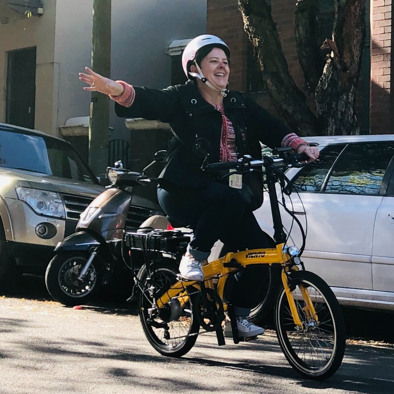 Woman riding a bicycle on a quiet city street in Sydney, hand signalling during a private road safety bike lesson