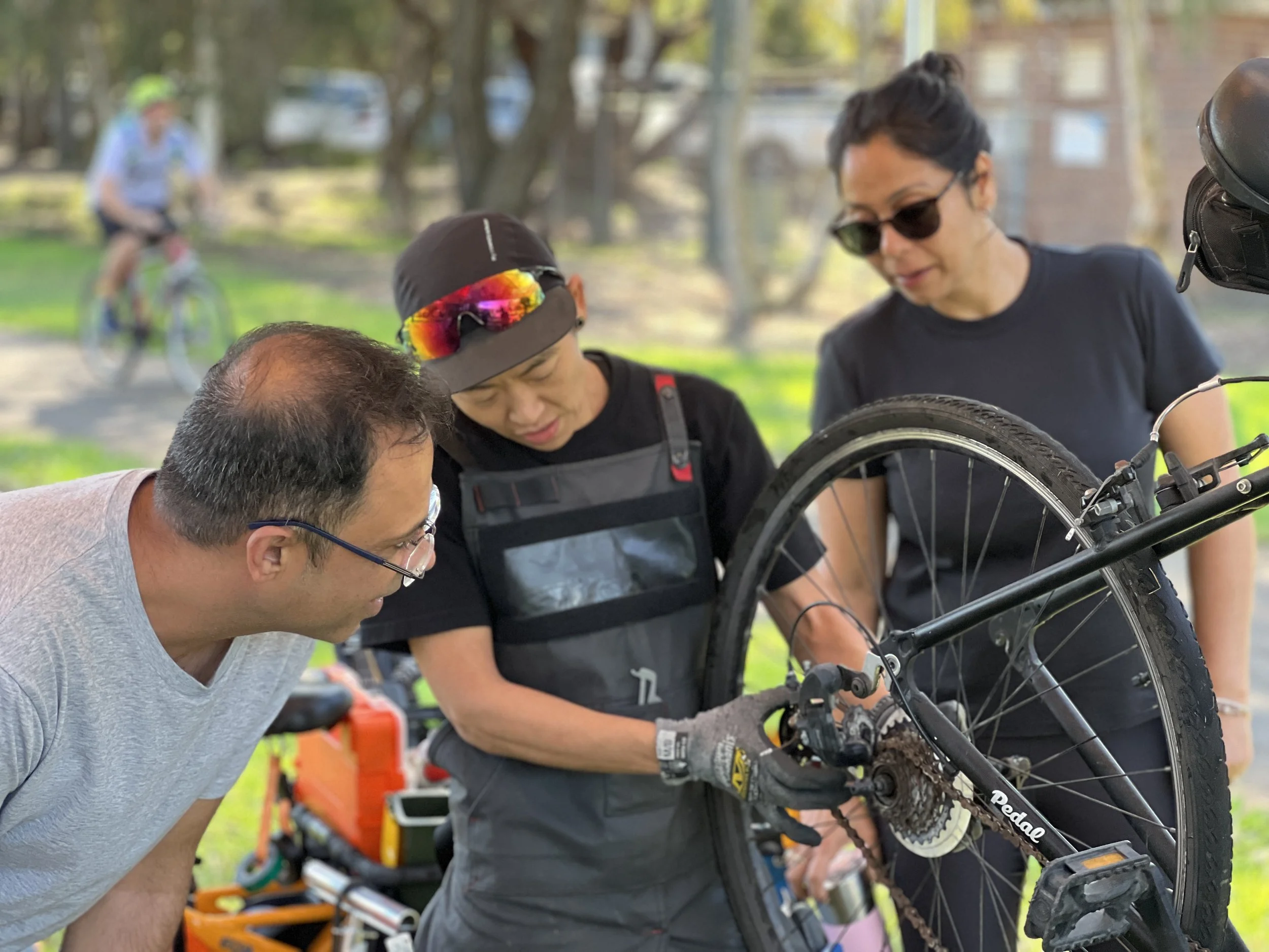 Pedal Set Go's woman mechanic showing a male and female bystander during free tune up how to clean the bicycle chain
