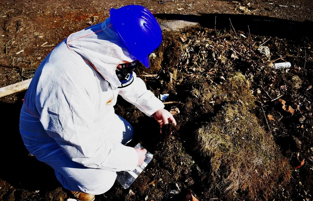Asbestos consultant inspecting suspect material within contaminated ground