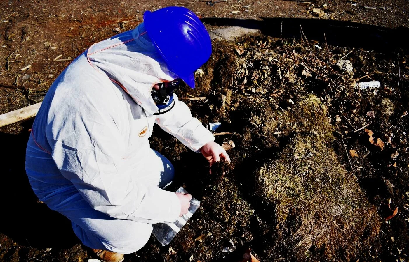 ASM asbestos specialist inspecting suspect material within contaminated ground