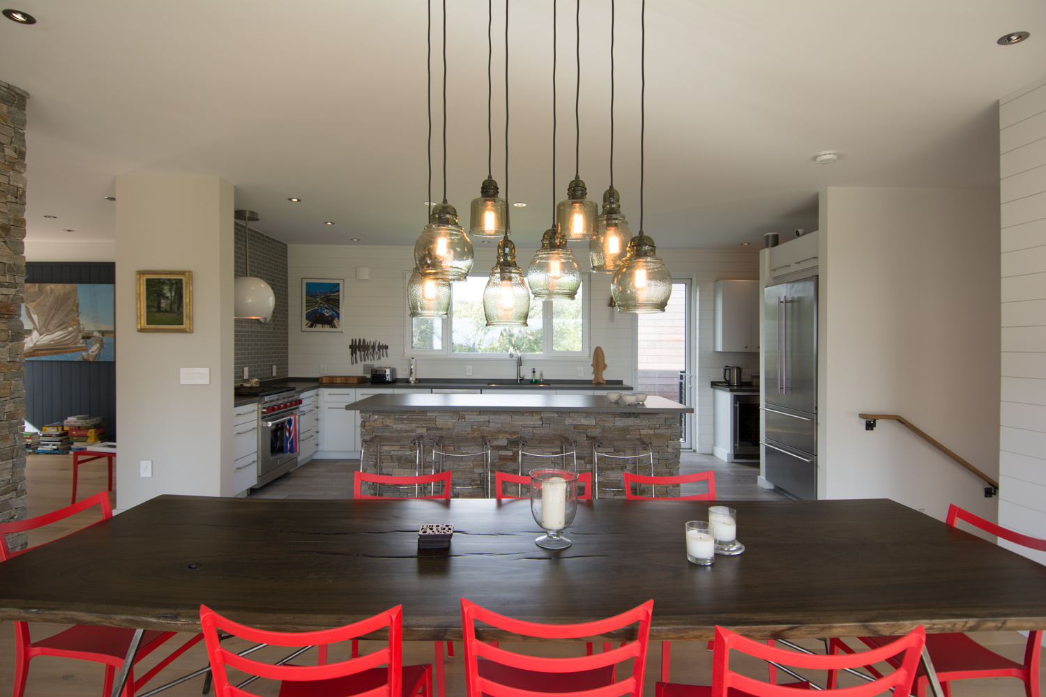 Open plan dining room and kitchen with red chairs and pendant lighting