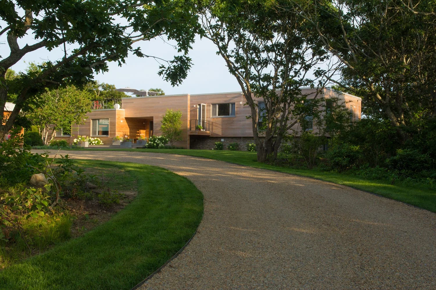 View of beach house from driveway through trees.