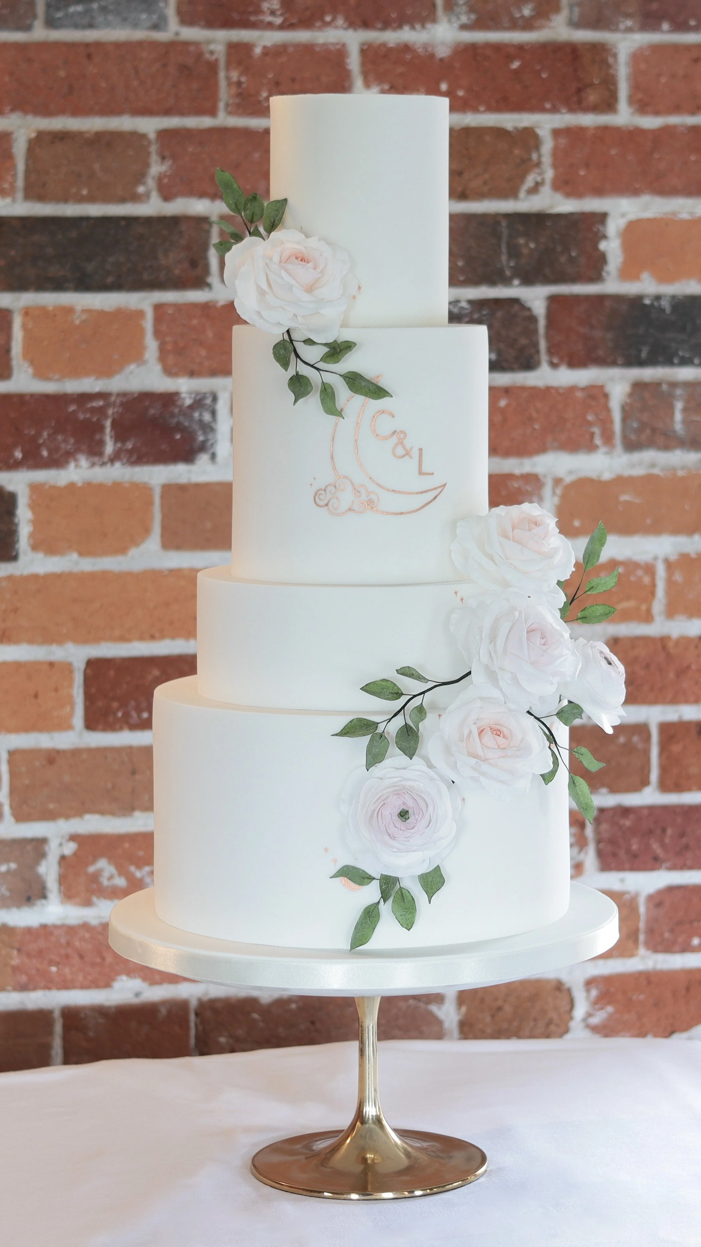 4 tier white wedding cake, wafer roses and leaves, with rose gold monogram detailing.jpeg