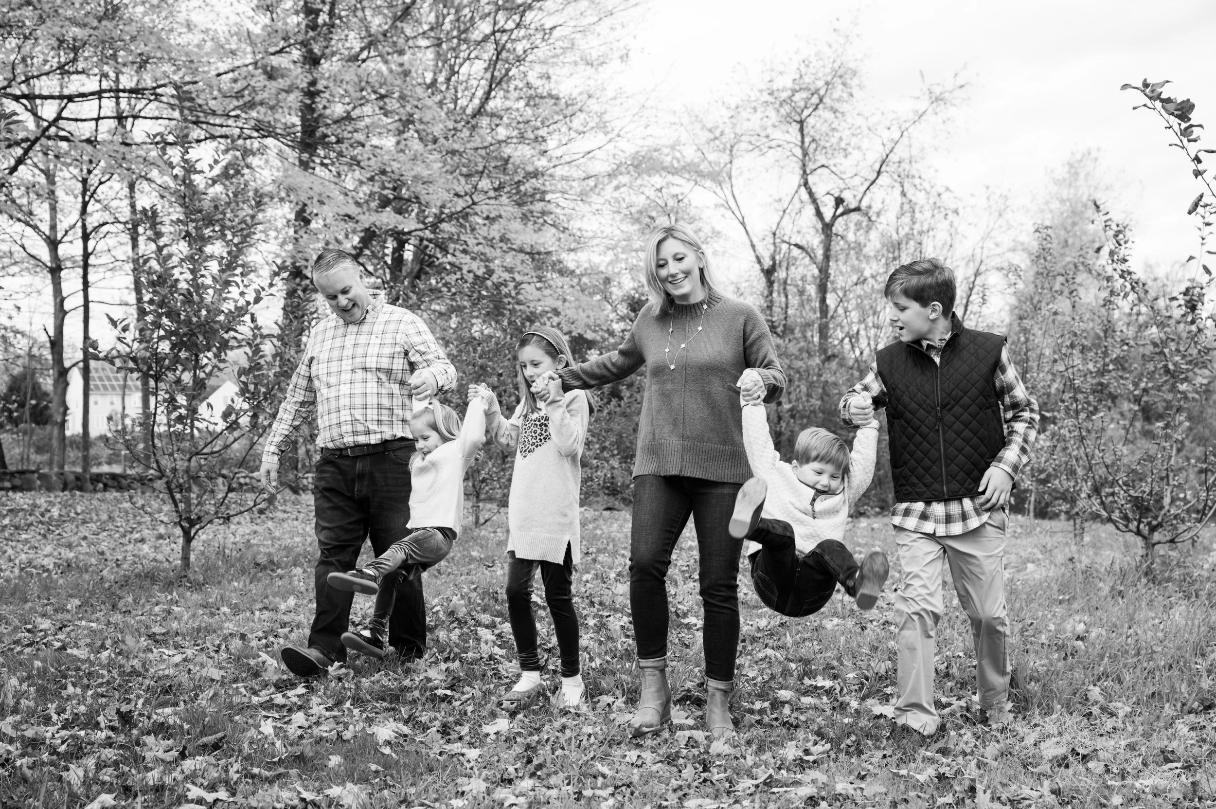 Black & white image of a family of six, walking in an orchard.