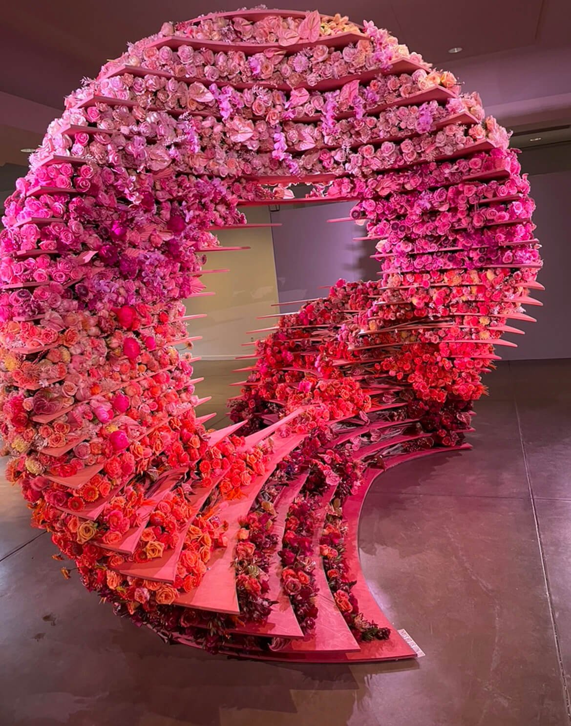 Side view of sculptural formation including more than 10,000 fresh-cut flowers, varying in size and texture, in an ombre palette inspired by the desert: terra cotta, orange, sand, pink, and blush.