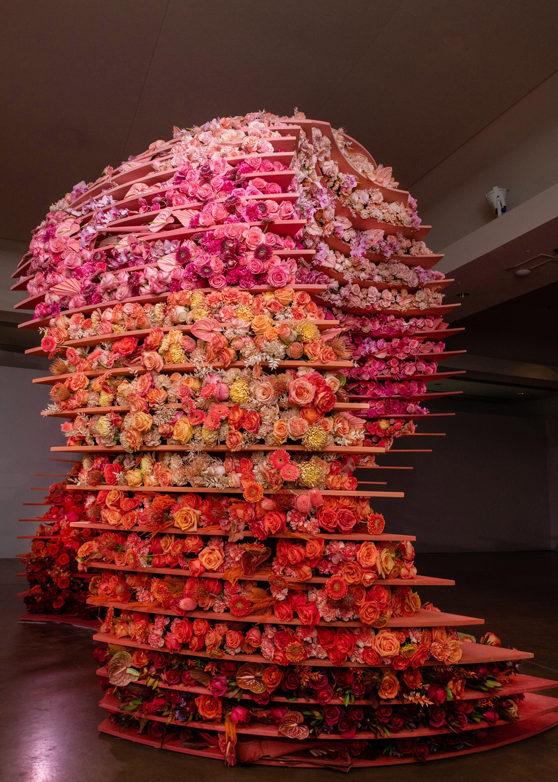 Side view of sculptural formation including more than 10,000 fresh-cut flowers, varying in size and texture, in an ombre palette inspired by the desert: terra cotta, orange, sand, pink, and blush.