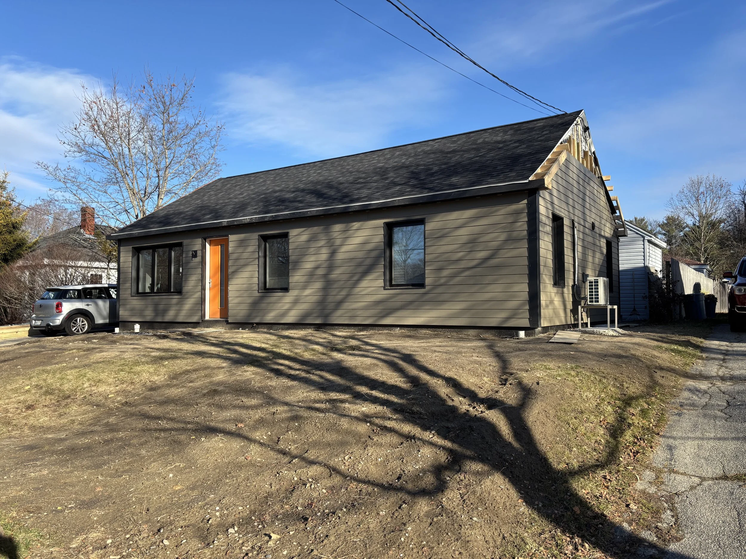 Single-story home with horizontal siding, dark trim, and an orange front door.