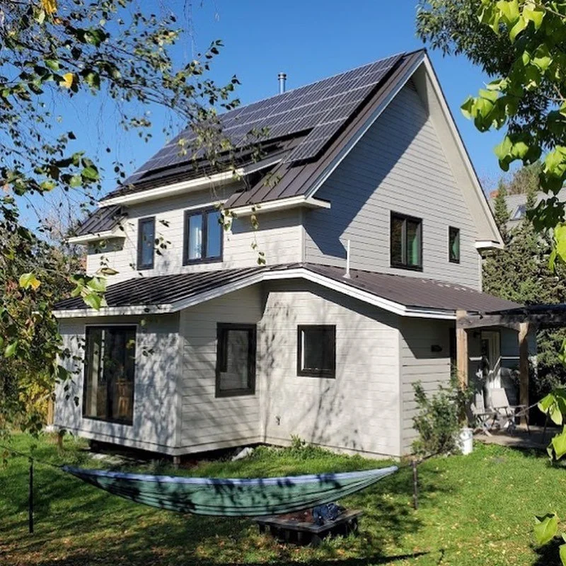 House exterior with light siding, dark trim, and rooftop solar panels.