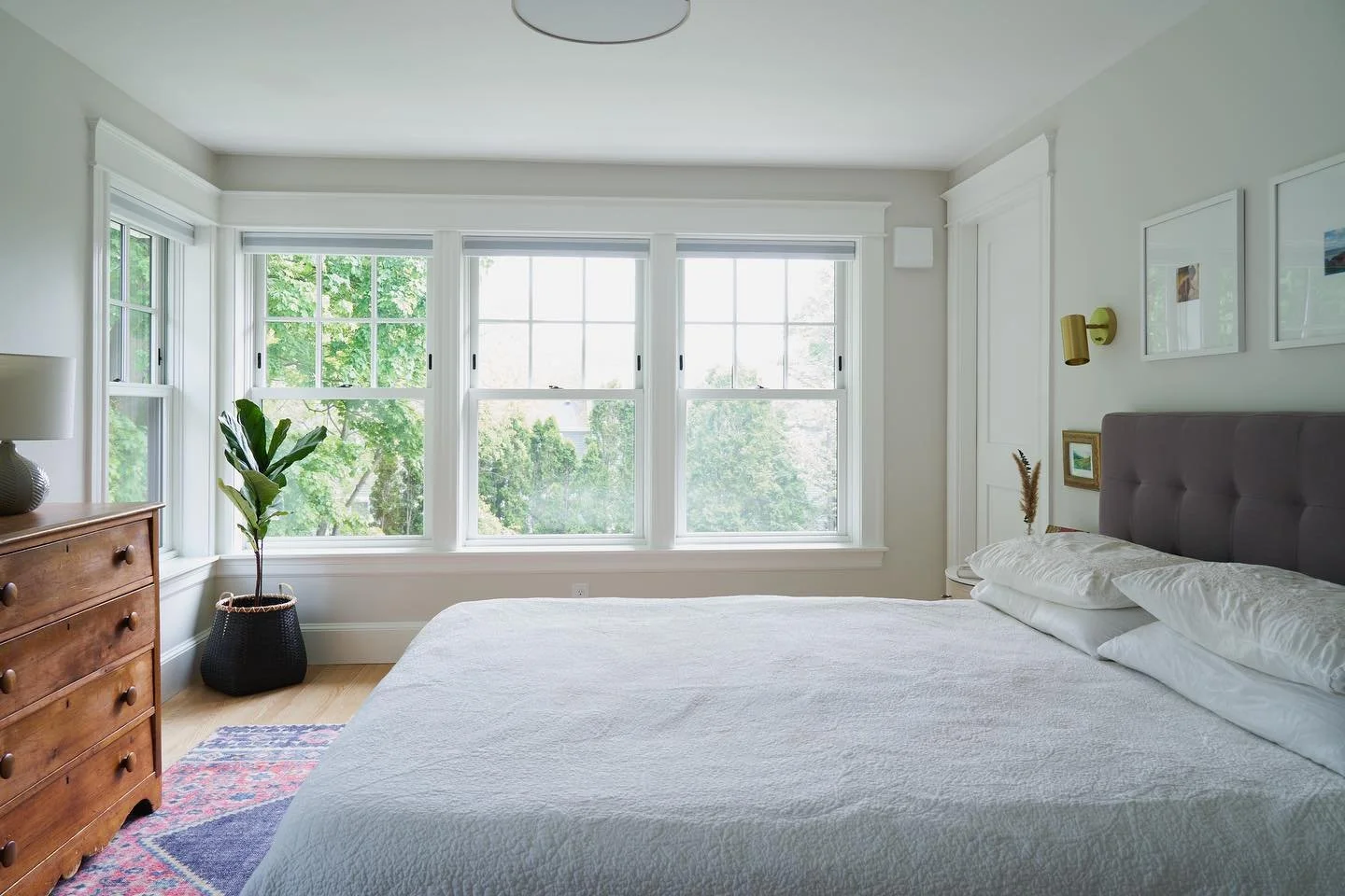 Bright bedroom with large windows overlooking trees.