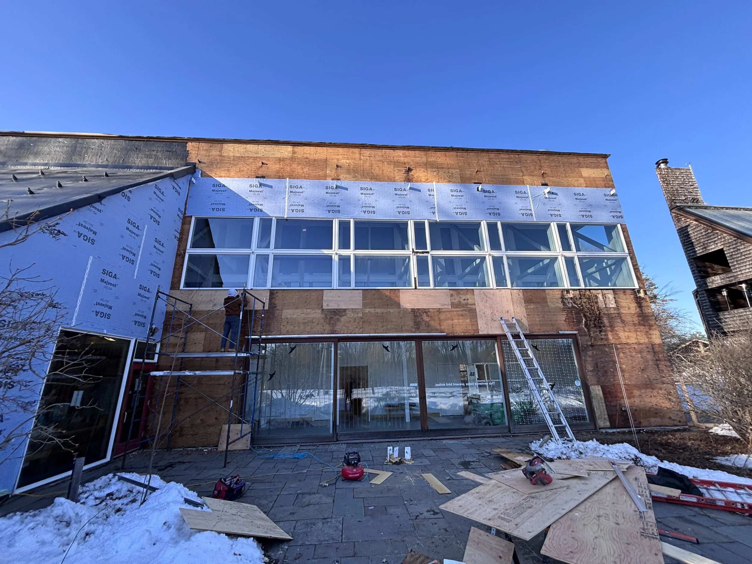 Maine Audubon education center during exterior renovation, with exposed wall layers and windows.