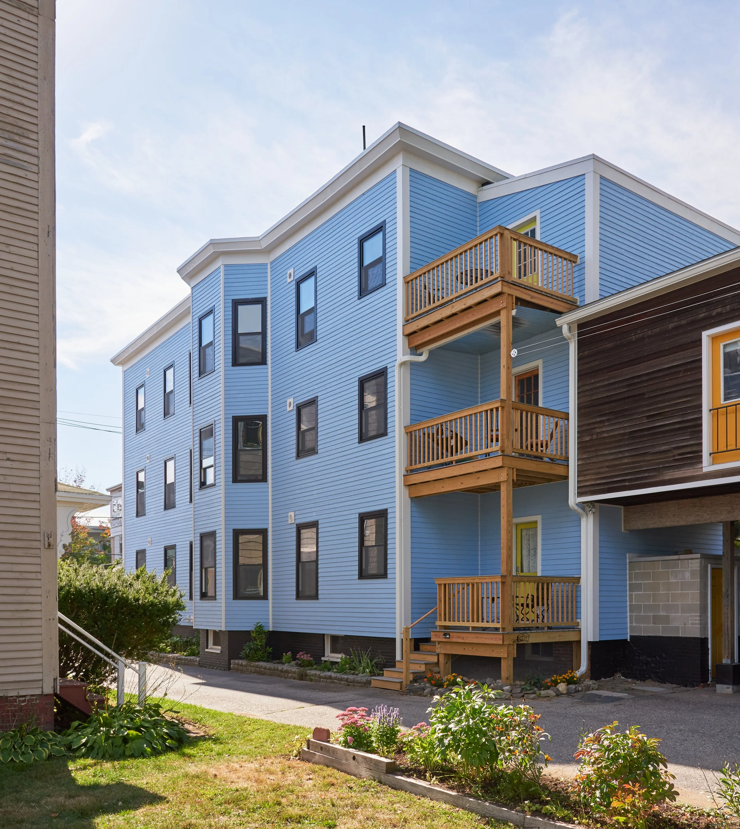 Blue three-story residential building with wood decks.