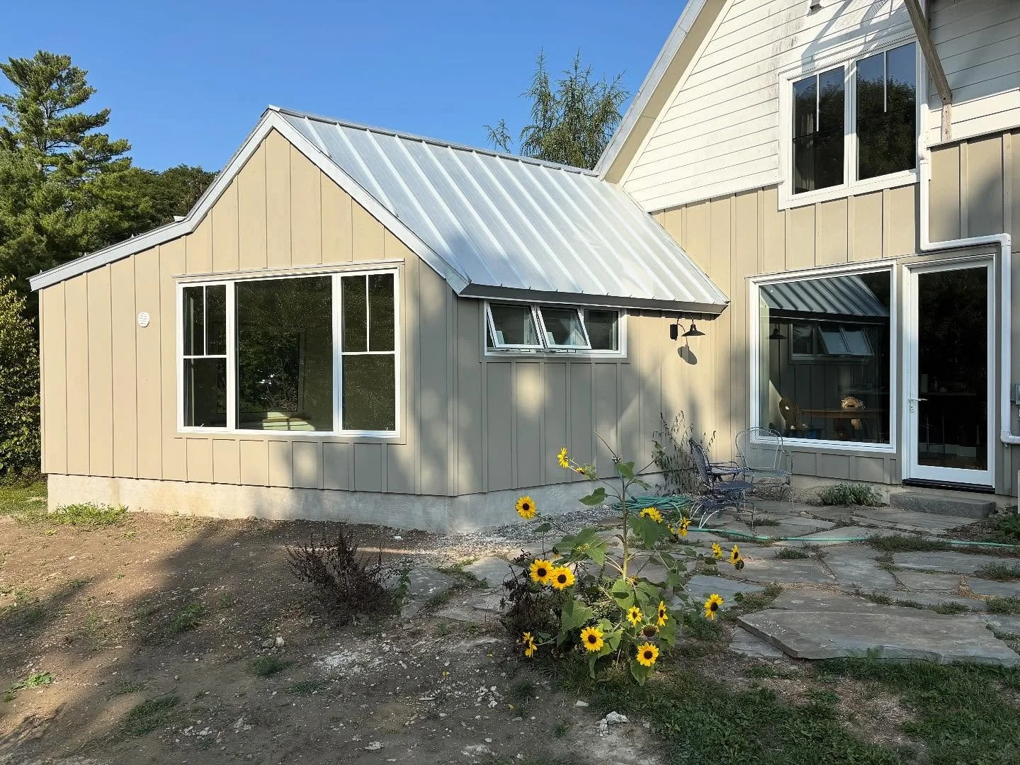 Attached ADU with a light-colored metal roof and large windows.