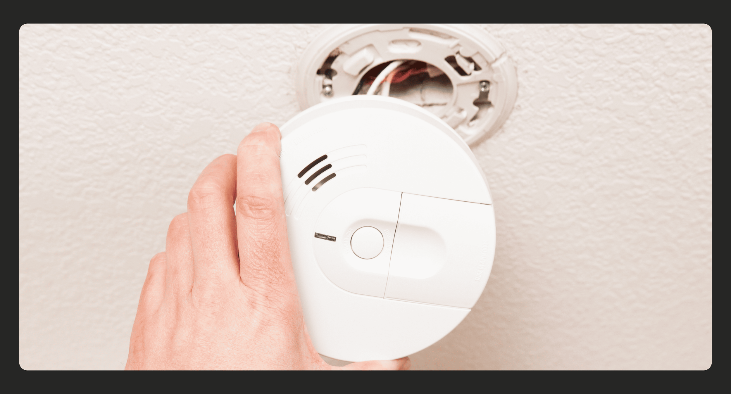photo of a photoelectric smoke alarm being held with wires showing