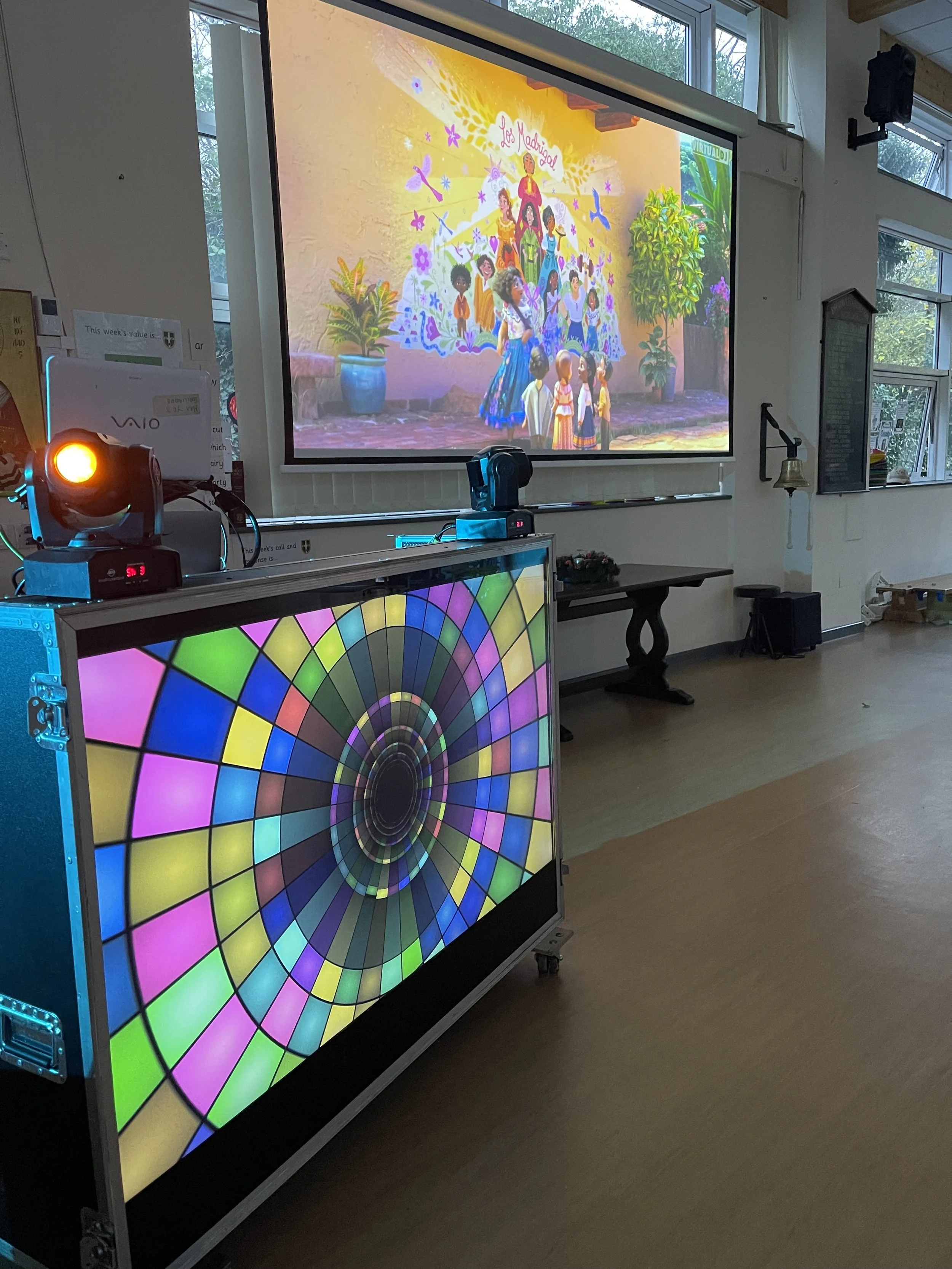 Classroom with a large screen displaying an animated movie scene above a colorful digital display stand.