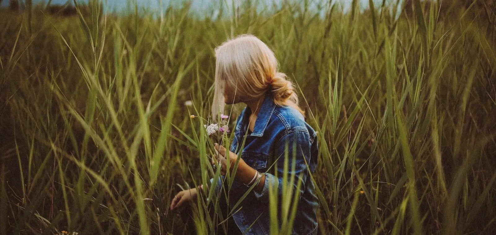 woman in long grass collecting flowers-min.jpg