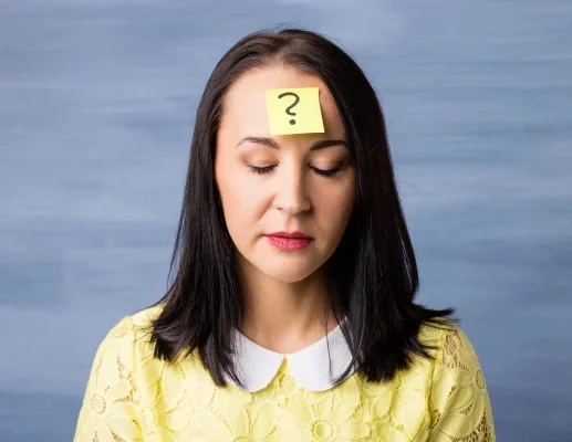 Woman in yellow shirt with yellow post-it note with question mark on her forehead