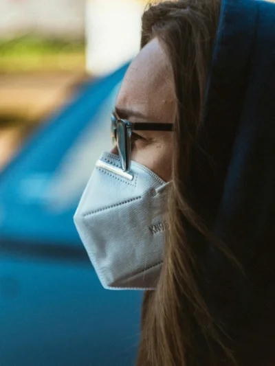 Profile view of woman wearing KN95 mask, eyeglasses, and hoodie