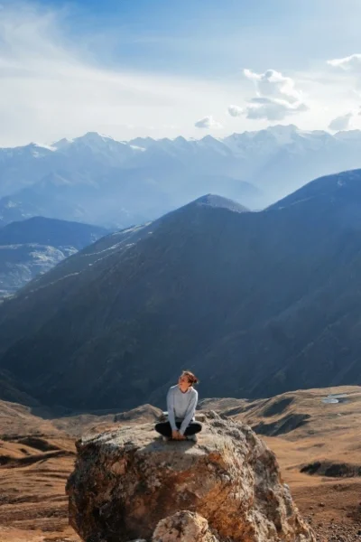 Woman sitting on rock on mountaintop in thought