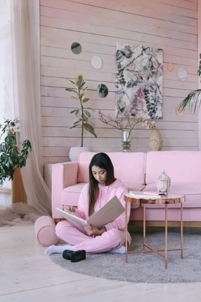 Woman sitting in pink PJs on floor looking at binder