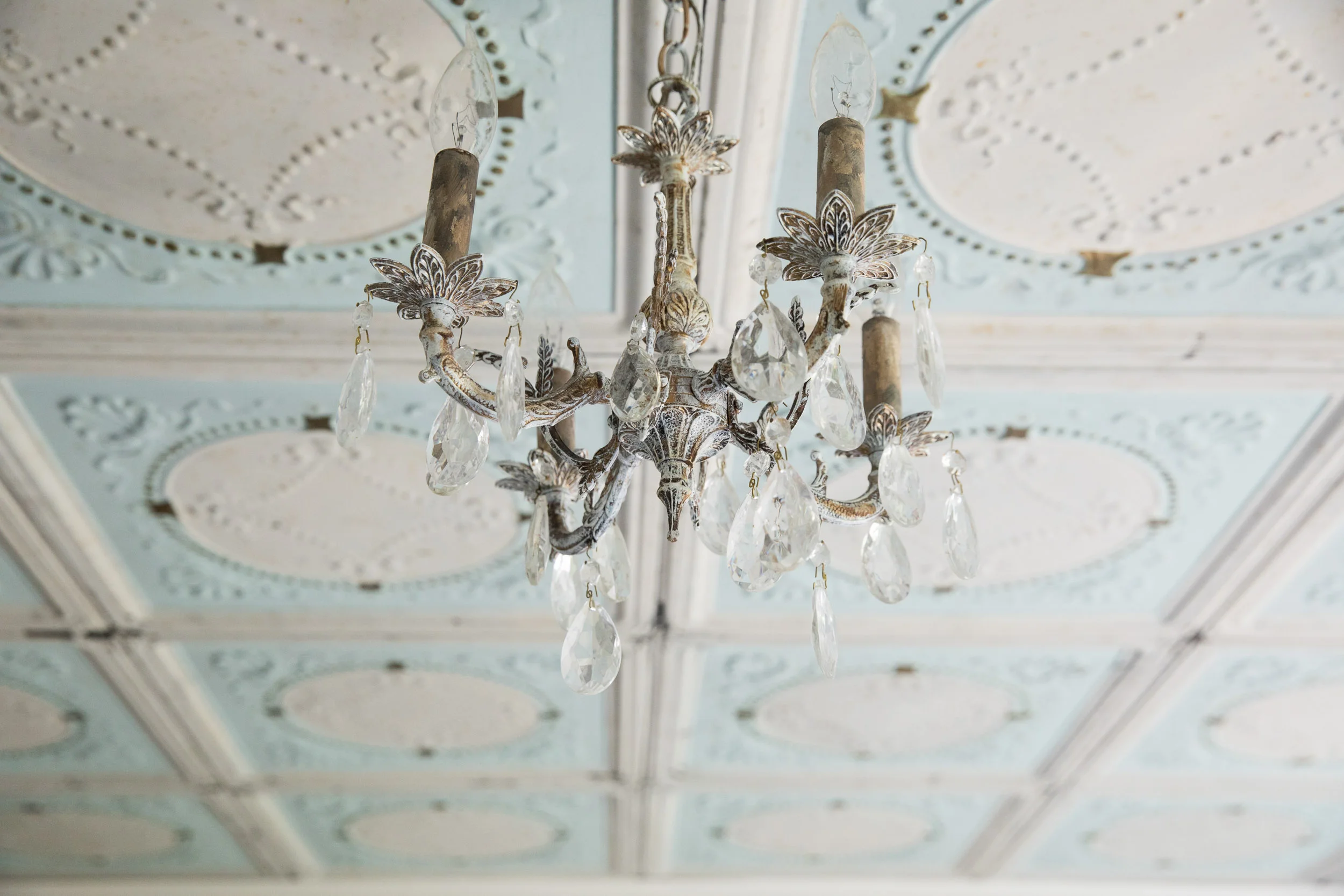 Salvaged blue and white tin ceiling tiles and an antique crystal and brass chandelier.