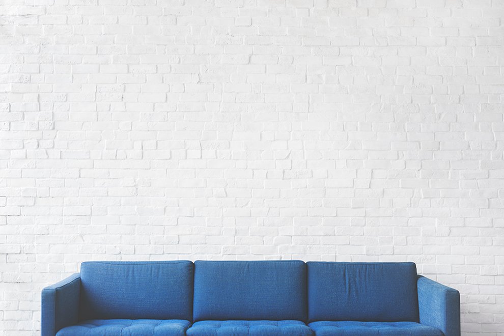 Blue Sofa against  a white brick wall