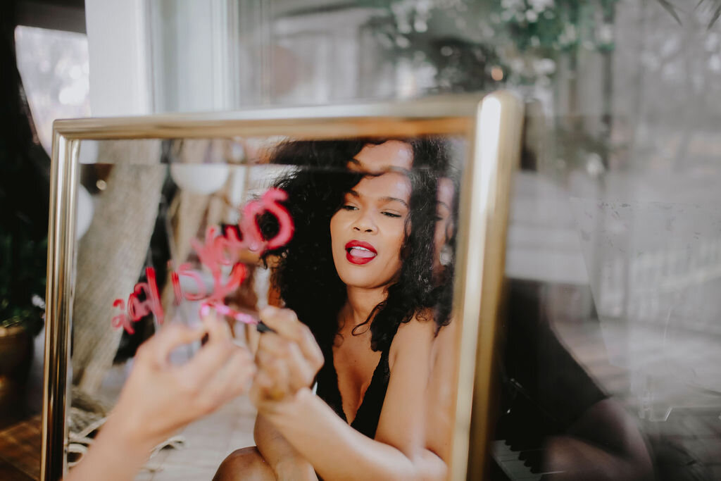 Black woman writing affirmations on a mirror.jpg