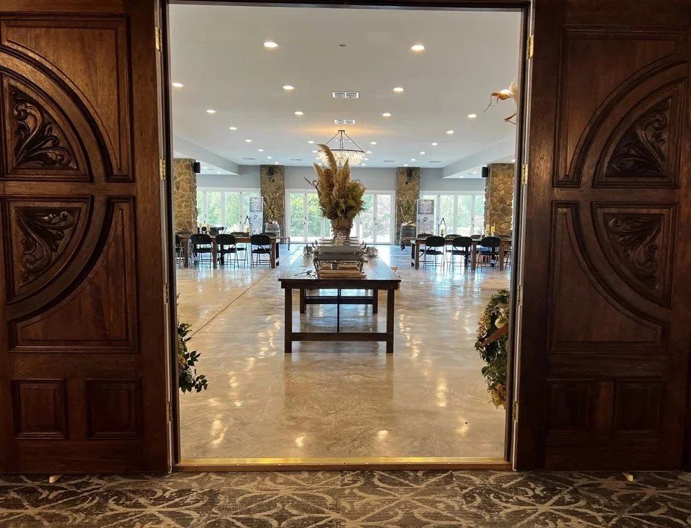 Reception set-up inside The Grand Pavilion at Homestead Hollow wedding and event venue in Springville, Alabama with stone columns and modern chandeliers.