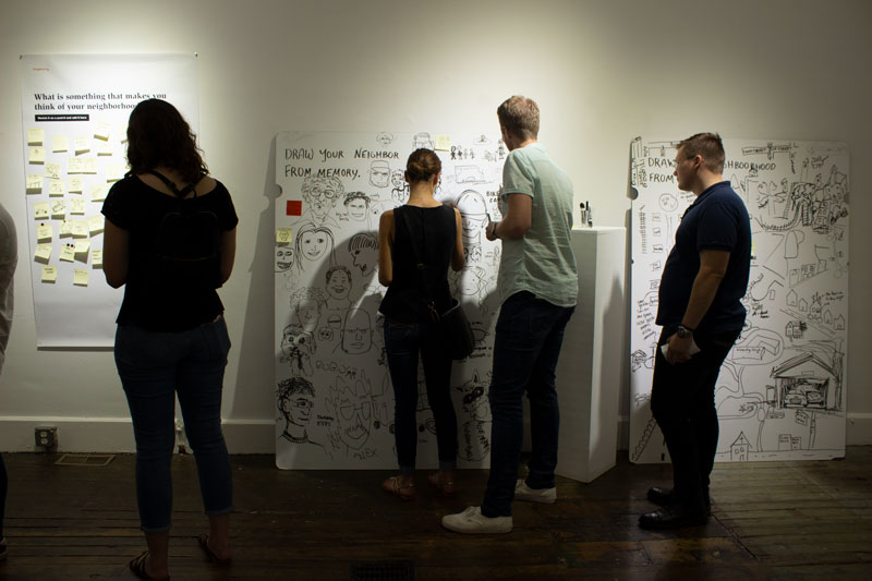Gallery goers adding to whiteboard drawings