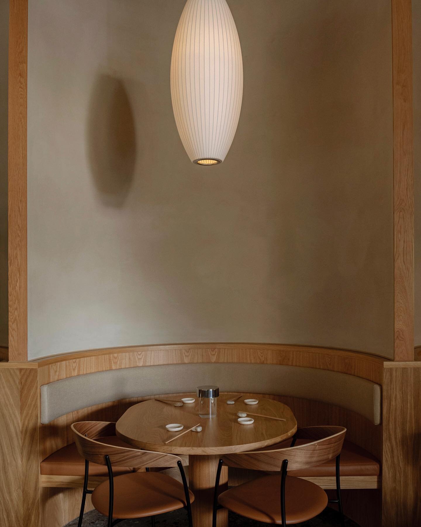 The rear scalloped wall finished in a sandy coloured clay and edged with oak is an elegant architectural expression that creates a dynamic focal point and a natural cocooning for group dining. The built-in seating is paired with custom-made oak table
