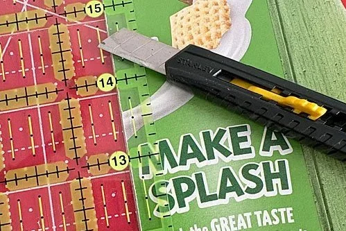 cutting cereal box strips with a carton knife and clear quilt ruler.