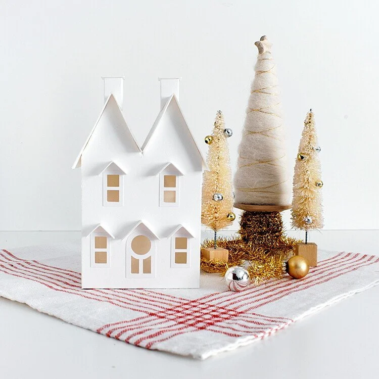 Full size white mantel house holiday decoration with three small Christmas trees decorated with gold and silver baubles on a white and red striped french tea towel.