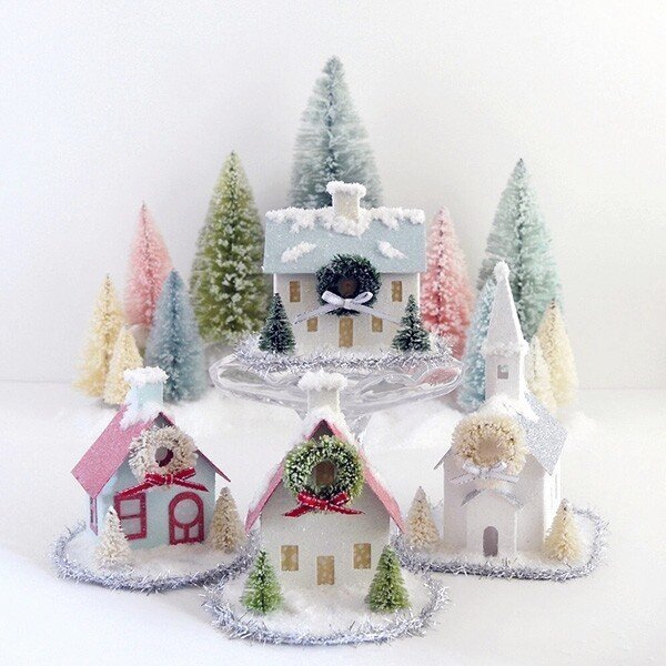 group of glittered putz house ornaments in front of multi color large bottle brush trees