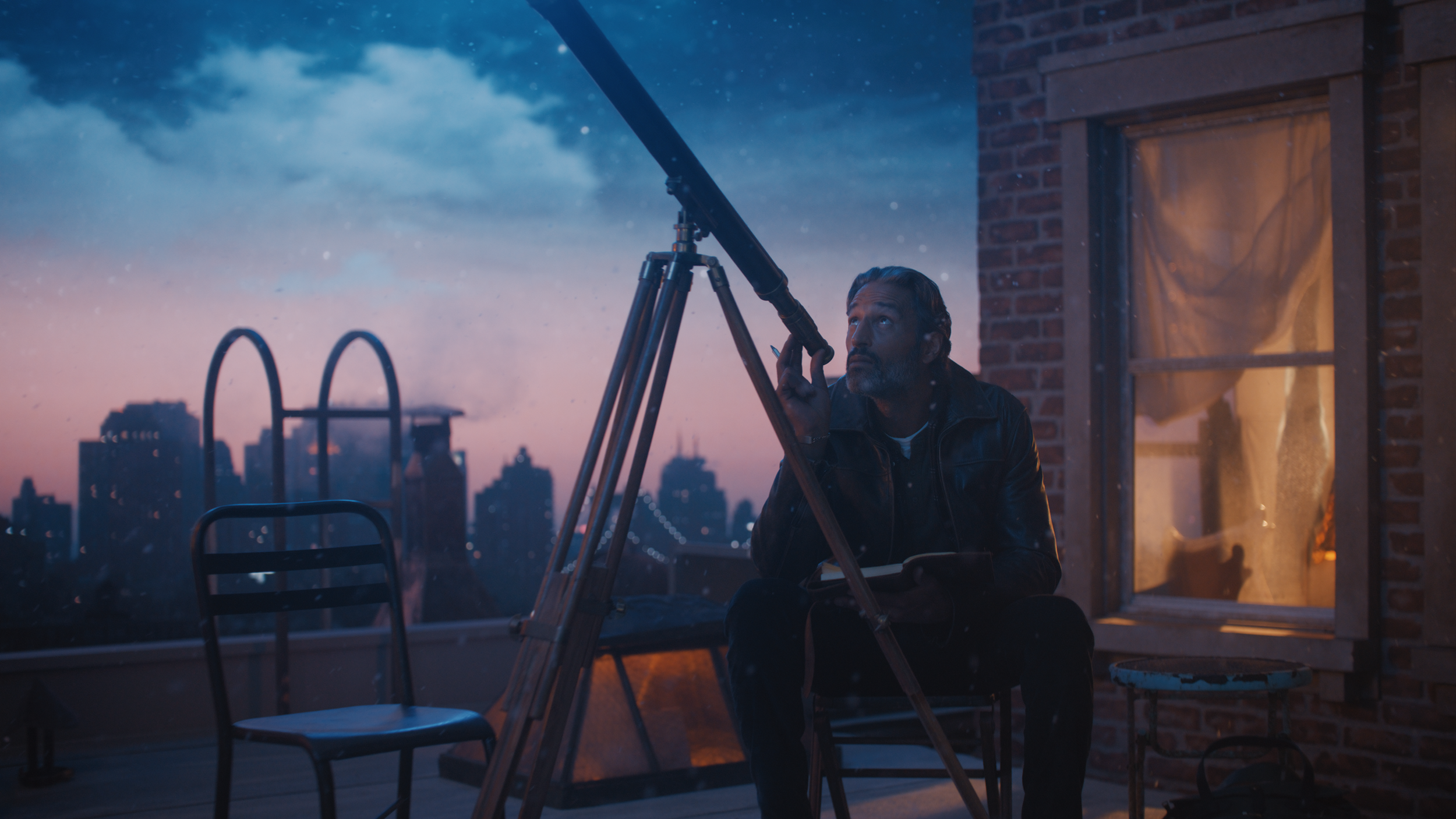 A man in a leather jacket looks up at the telescope on a rooftop during sunset, with city skyline in the background.