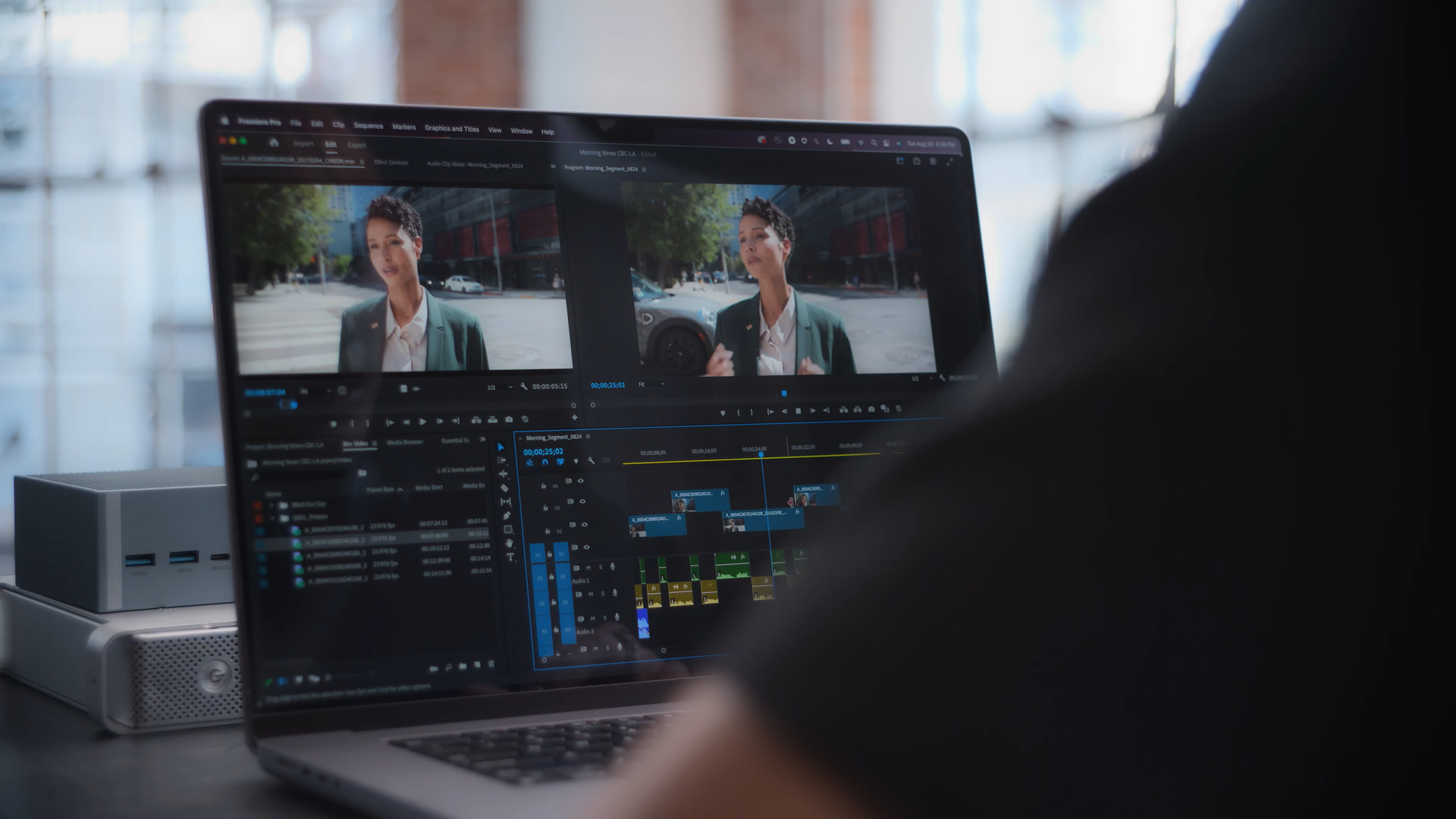 A person works on video editing on a laptop, with a second screen displaying the edited video of a woman outdoors in the city.