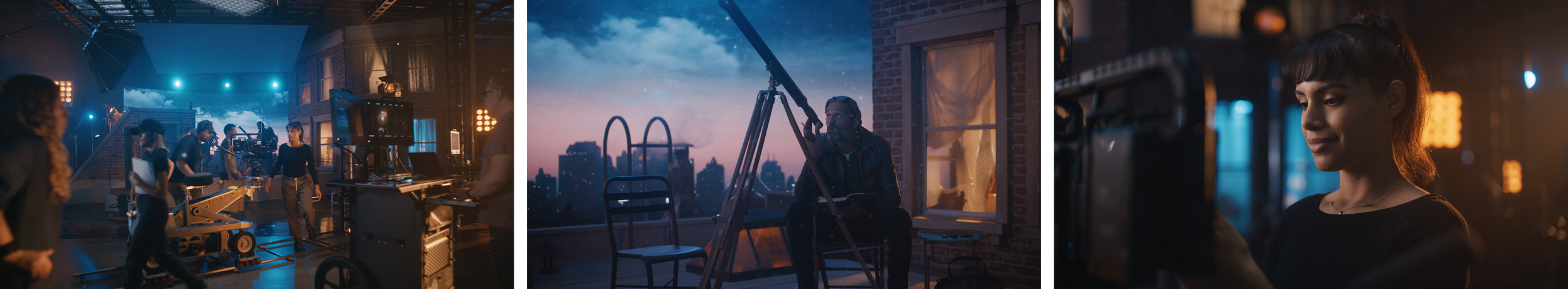 Filmmaking set on a rooftop at dusk, with crew members, a camera on a dolly, a woman with a clipboard, a man sitting on a window ledge with a camera, and a woman operating a camera, illuminated by studio lights and city skyline in the background.