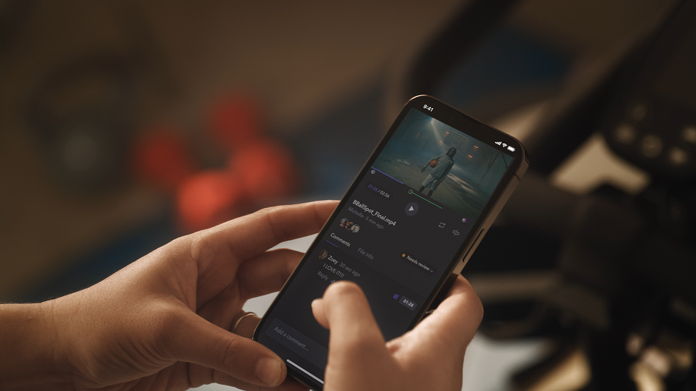 Person holding a smartphone while editing or viewing a video on the phone.
