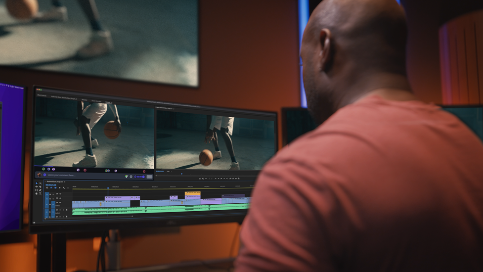 A person editing a sports video on a computer monitor, showing a basketball player dribbling on the court.