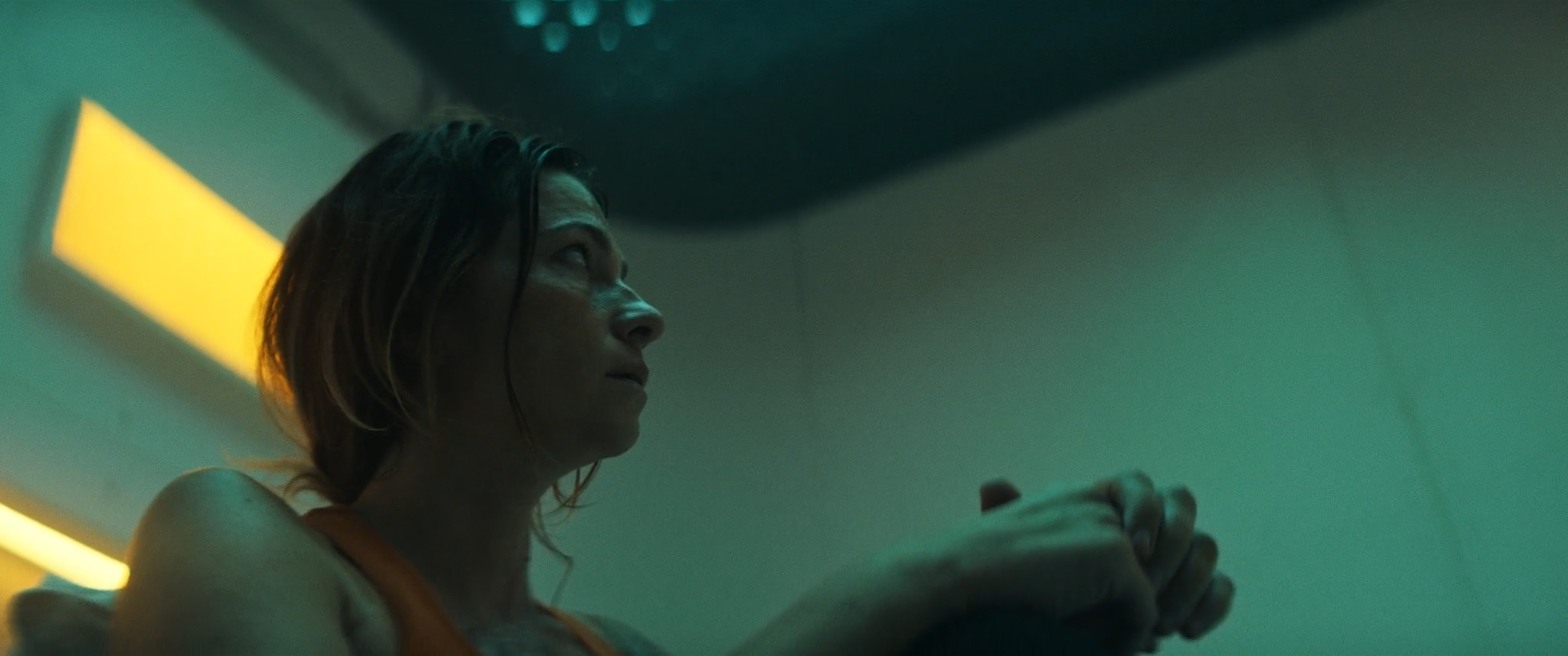 A woman with wet hair looking at her phone in a dimly lit room with green lighting.
