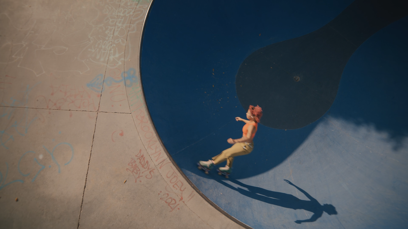 Person roller skating in a skate park bowl with a shadow cast on the blue surface.
