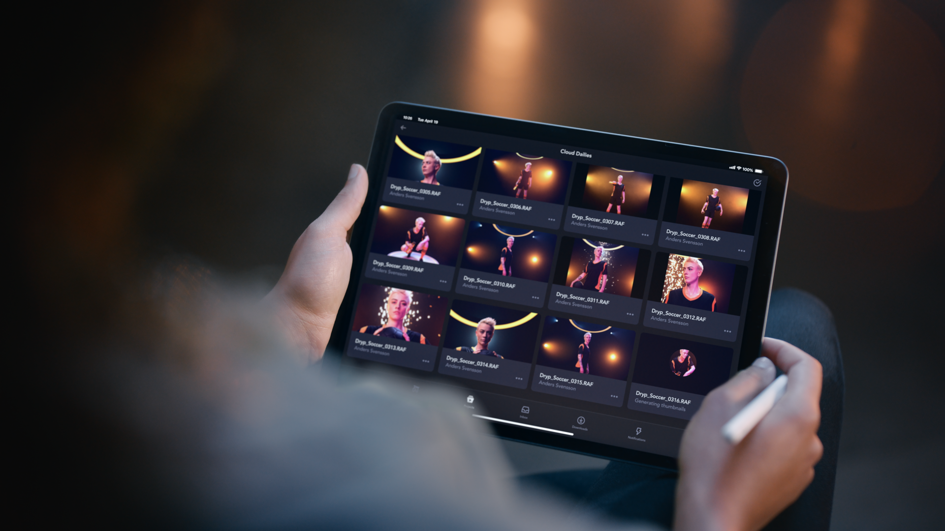 Person holding a tablet displaying images and videos of a woman playing soccer, with a dark background and light reflections.