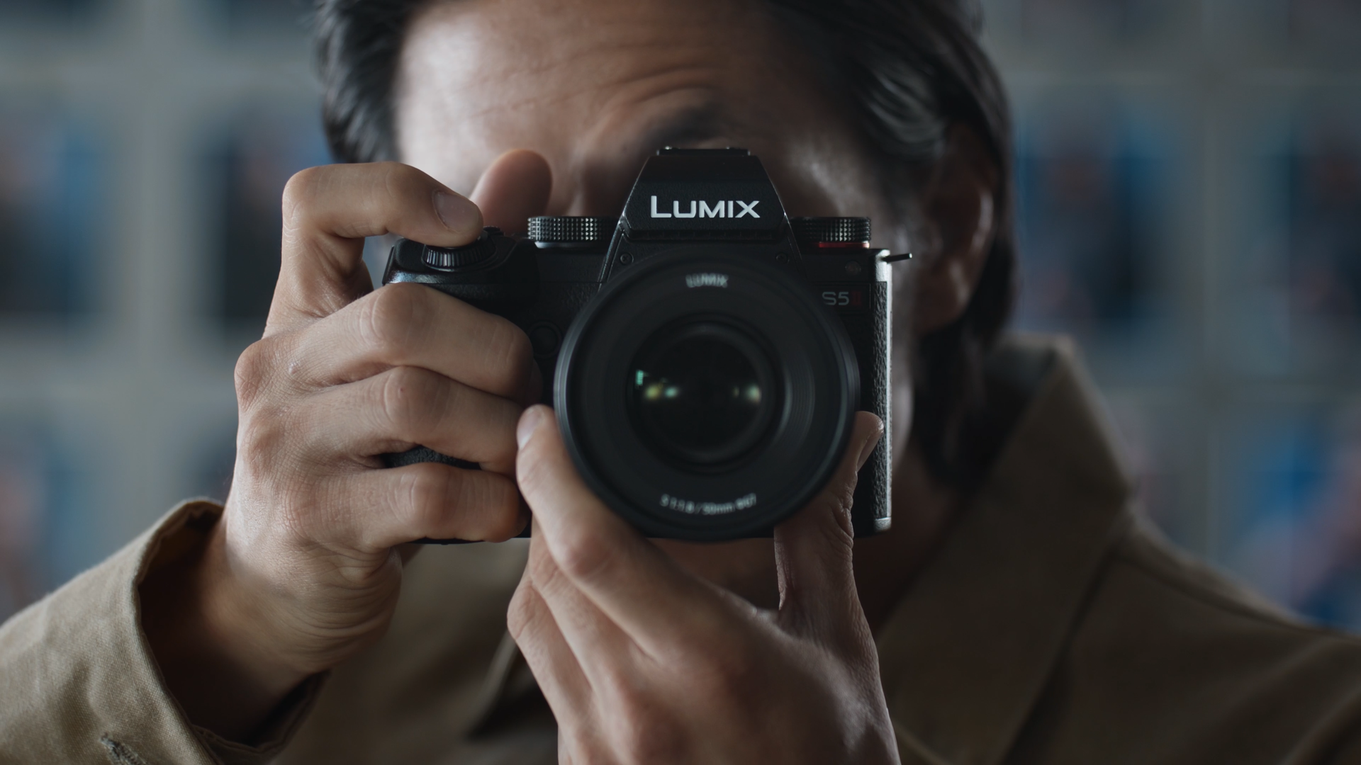 Person holding a Lumix camera up to their face, taking a photograph.