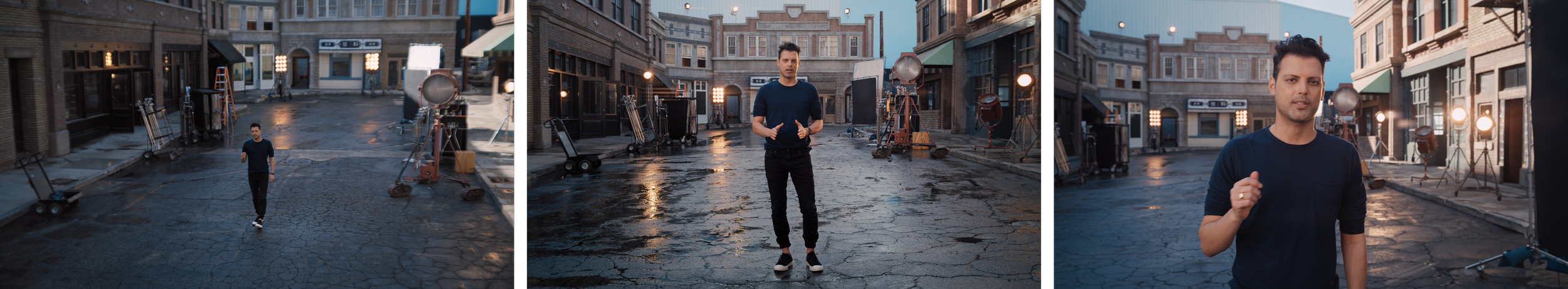 A man standing in the middle of an outdoor film or video shoot setting on a city street at twilight. The street is wet, and the setup includes professional lighting equipment and crew members.