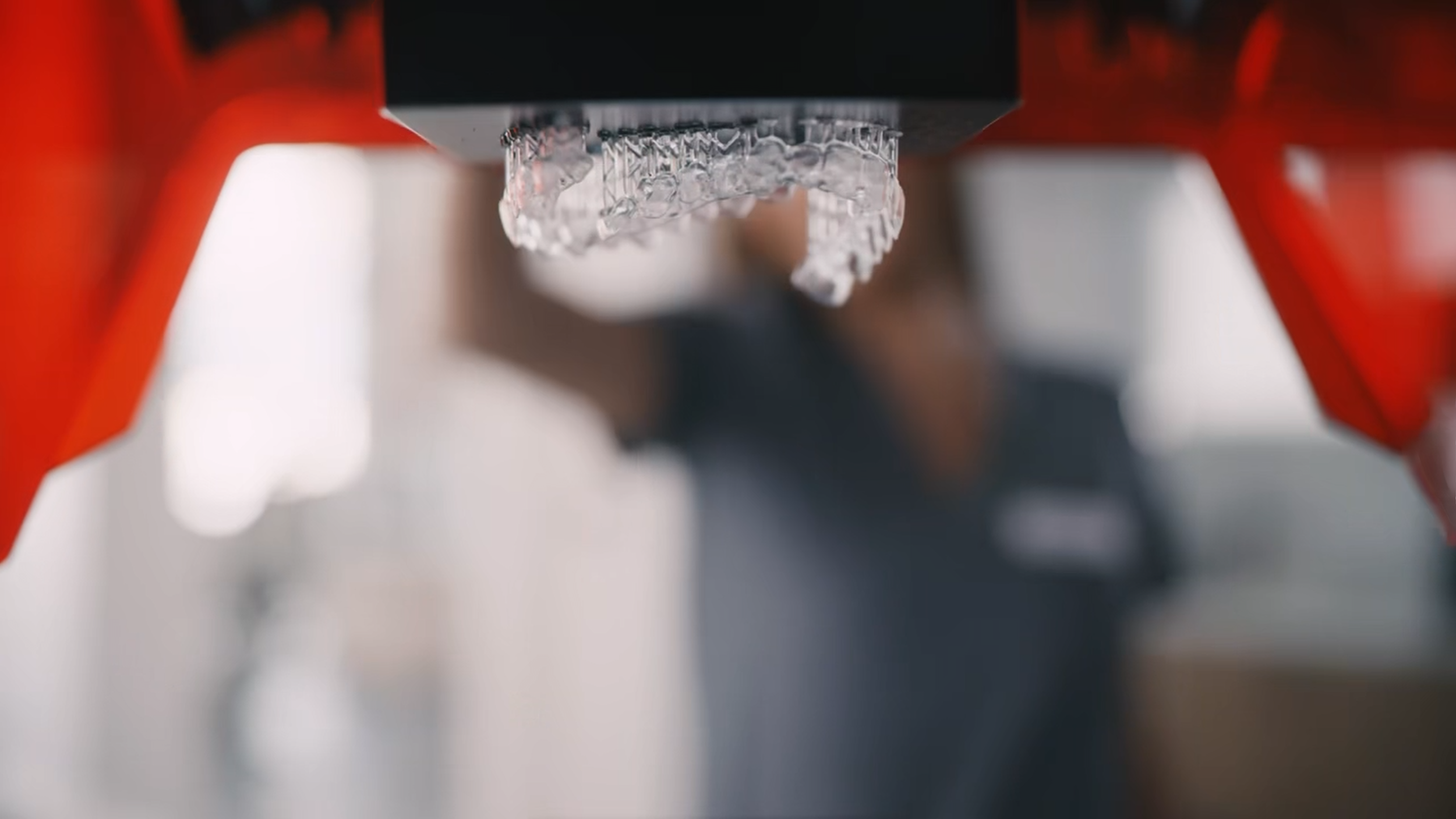 Close-up of a dental mold or aligner being positioned inside a 3D Dental Printer, with red components supporting it.